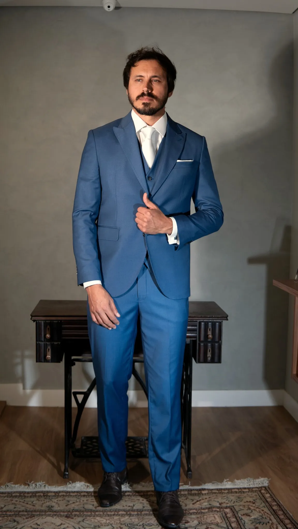 Terno azul royal com colete, de corpo inteiro, com o punho da camisa aparecendo na manga