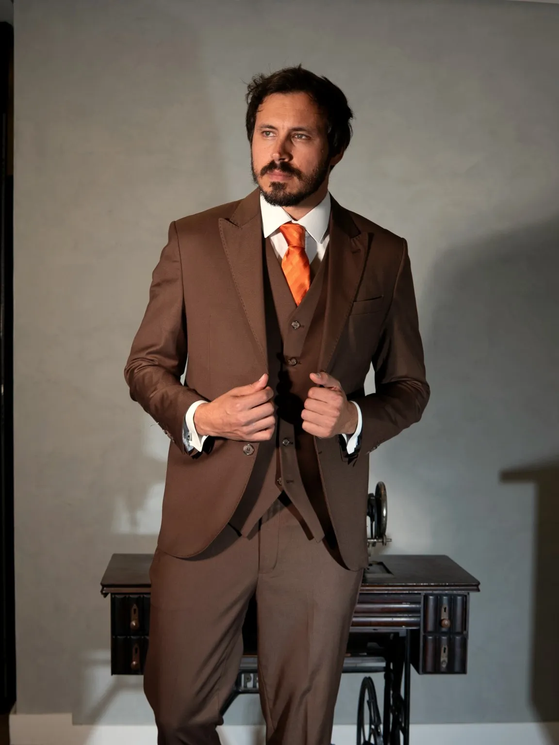 Terno três peças marrom com gravata laranja, de lado